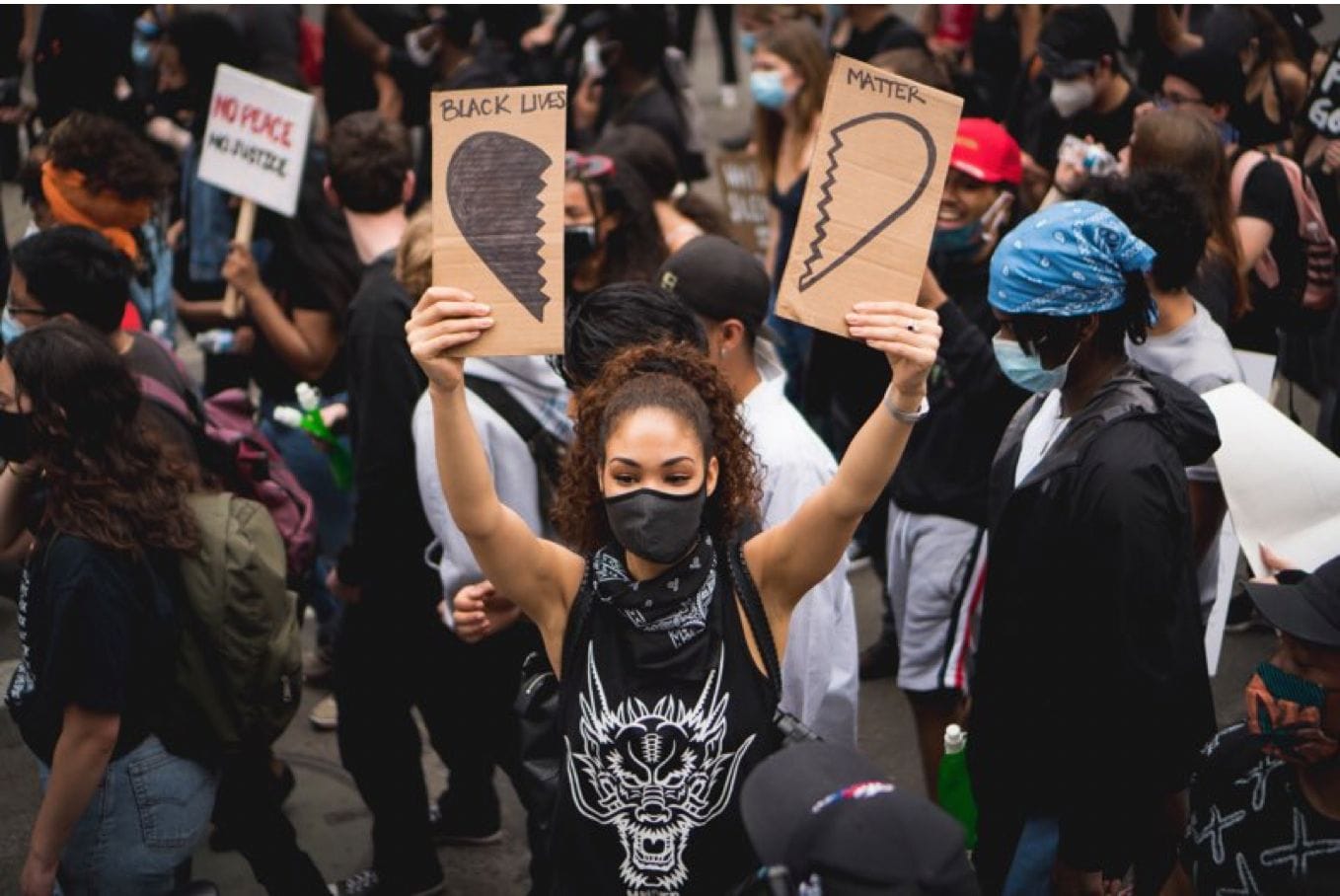 Woman at protest with sign saying Black Lives Matter with an image of a broken heart.